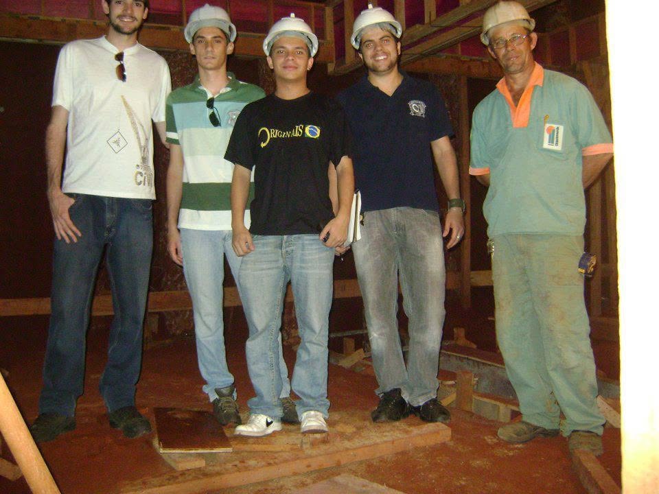 Marcos e equipe de capacete dentro de obra em estrutura de madeira